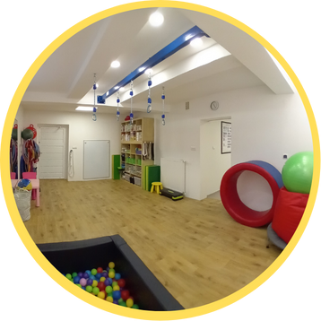 Sala integracji sensorycznej na której widać belkę do podwieszeń, basen z kulkami i inne przyrządy